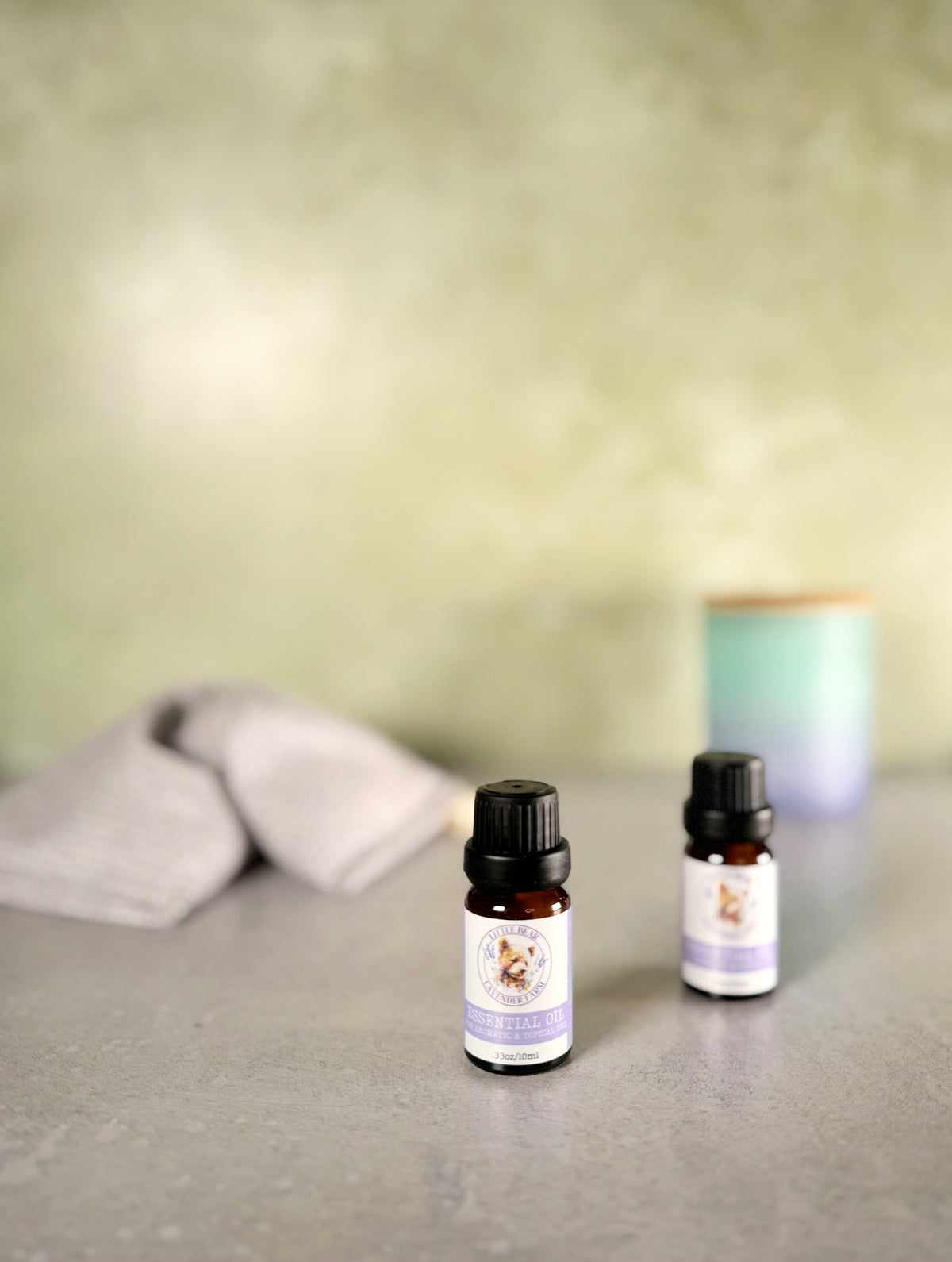 Two 10 ml bottles of steam-distilled lavender essential oil beside a diffuser and a lavender eye pillow